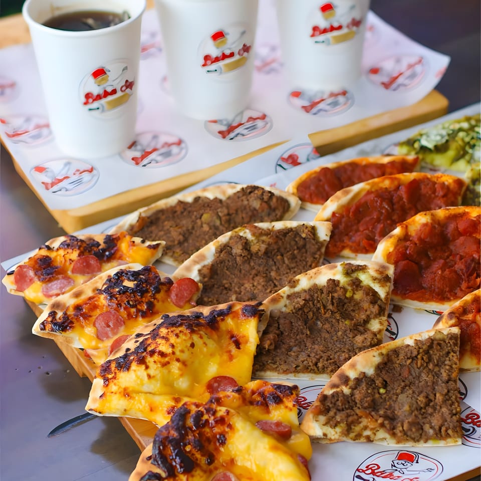 Assorted Turkish flatbreads topped with cheese, pepperoni, and minced meat served alongside three cups of tea.